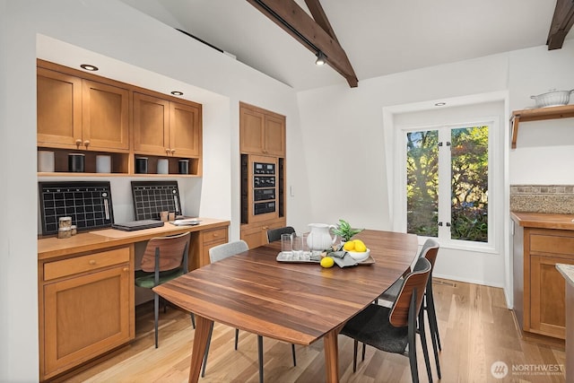 dining room featuring wine cooler, built in study area, light wood-type flooring, and beam ceiling
