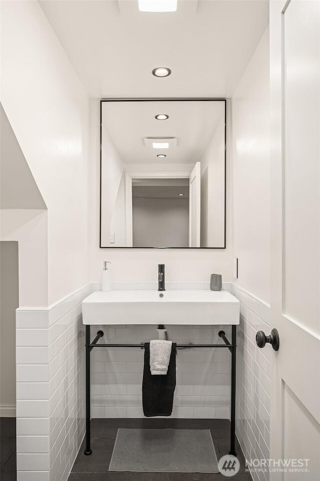 bathroom with recessed lighting, a sink, a wainscoted wall, and tile walls