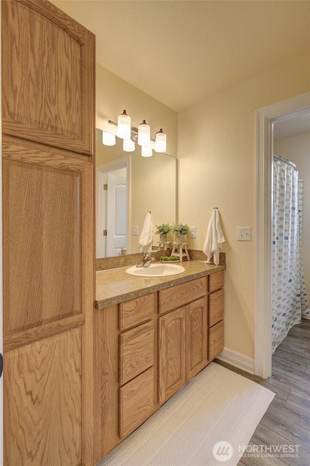 bathroom featuring vanity, baseboards, and wood finished floors