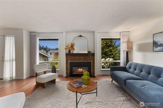living room featuring a textured ceiling, a brick fireplace, and wood finished floors