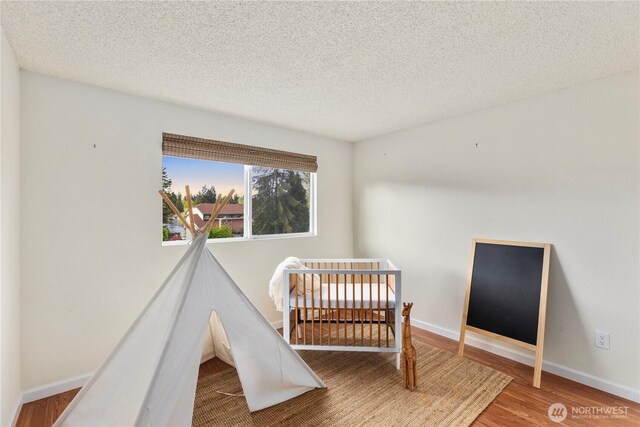 bedroom with baseboards, a textured ceiling, and wood finished floors