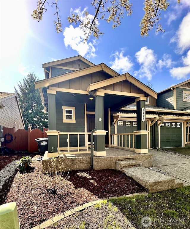 view of front of home featuring fence, board and batten siding, an attached garage, and a porch