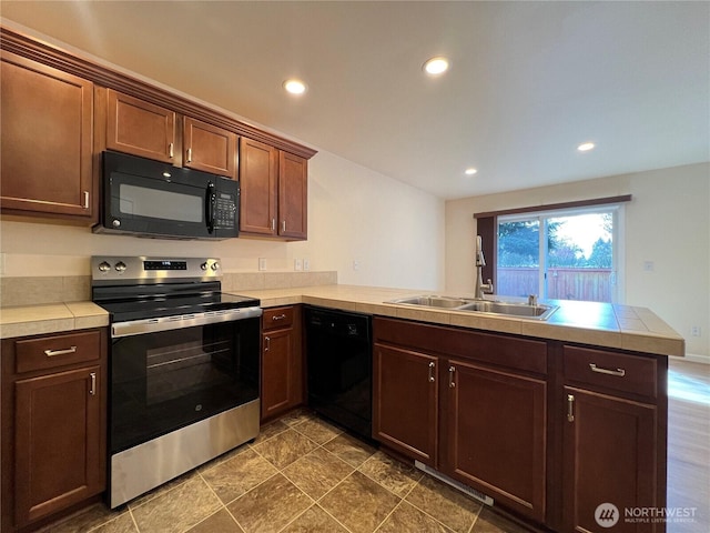 kitchen featuring recessed lighting, a sink, a peninsula, and black appliances
