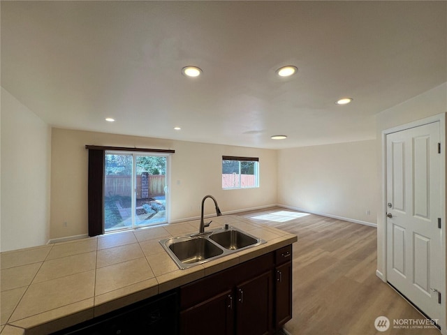 kitchen featuring dark brown cabinets, tile countertops, a sink, light wood-style flooring, and dishwasher