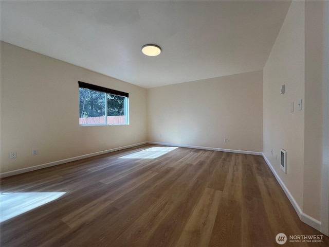 spare room featuring visible vents, baseboards, and wood finished floors