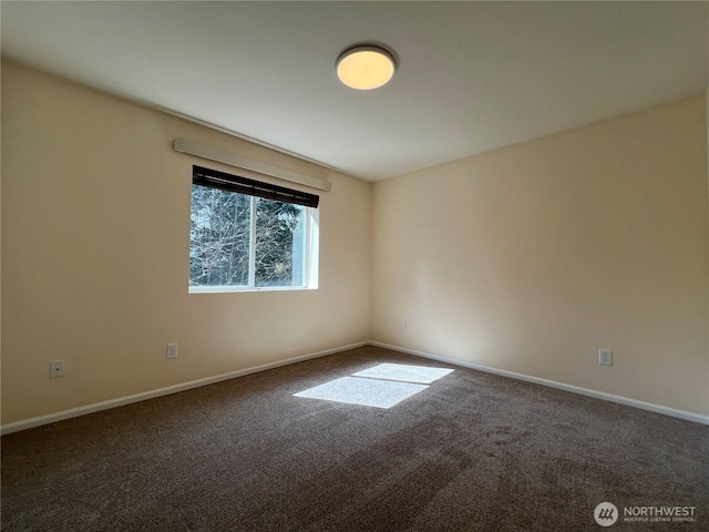 carpeted empty room featuring baseboards