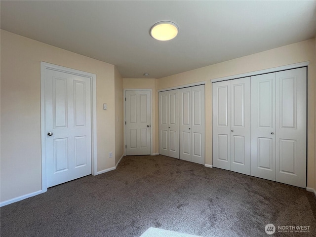 unfurnished bedroom featuring carpet flooring, baseboards, and two closets