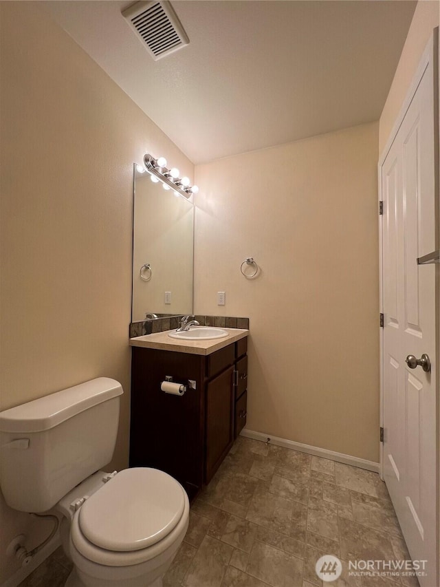 half bath featuring visible vents, baseboards, toilet, and vanity