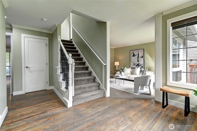 stairway featuring baseboards, ornamental molding, and wood finished floors