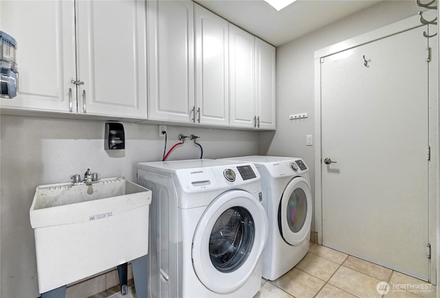 clothes washing area with a sink, light tile patterned floors, independent washer and dryer, and cabinet space