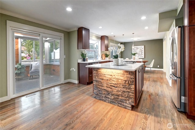 kitchen with baseboards, freestanding refrigerator, light countertops, and a center island