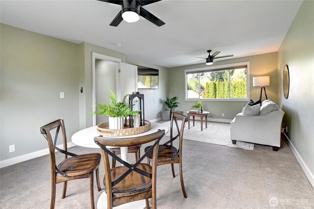 carpeted dining space with baseboards and ceiling fan