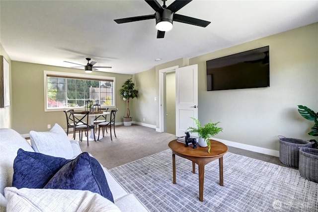 carpeted living room featuring baseboards and a ceiling fan