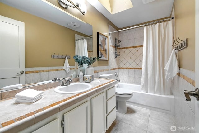 full bath featuring a skylight, tile patterned floors, vanity, toilet, and shower / bath combo with shower curtain