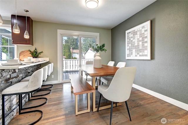 dining space with baseboards, a healthy amount of sunlight, and dark wood-style floors