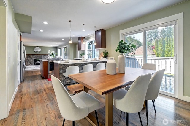 dining area featuring recessed lighting, baseboards, dark wood finished floors, and a fireplace