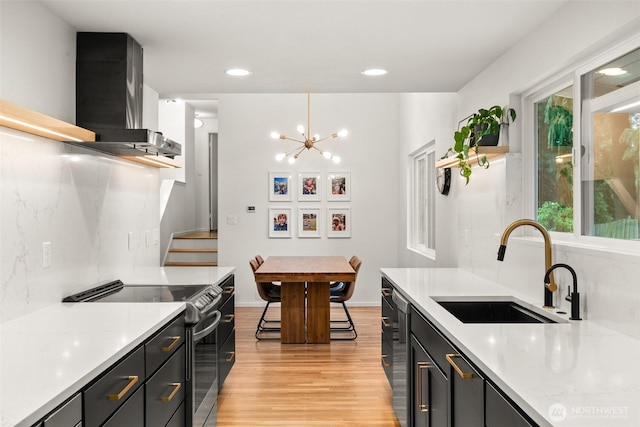 kitchen with appliances with stainless steel finishes, a sink, light countertops, extractor fan, and light wood-style flooring