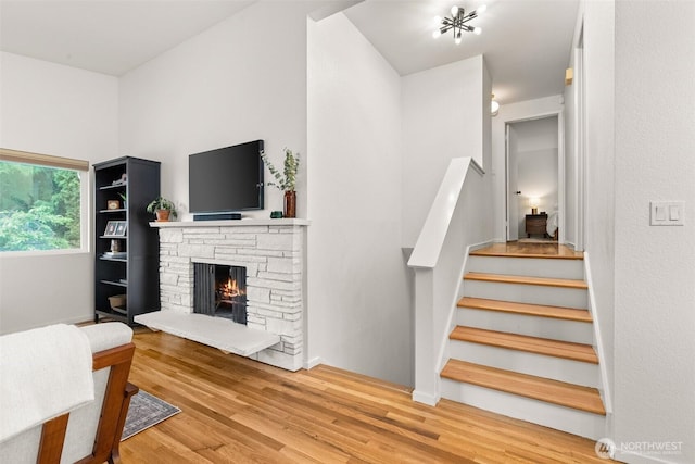 living area with a fireplace, stairs, and wood finished floors