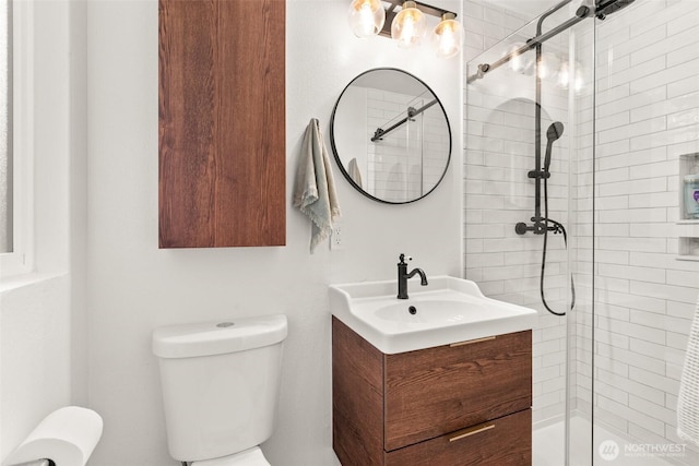 bathroom featuring toilet, a tile shower, and vanity