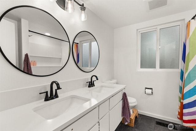 bathroom featuring double vanity, toilet, visible vents, and a sink
