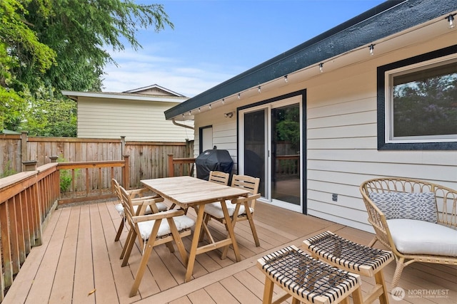 wooden terrace with fence, outdoor dining space, and grilling area