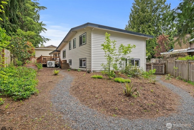 view of side of home with ac unit, fence, and a deck