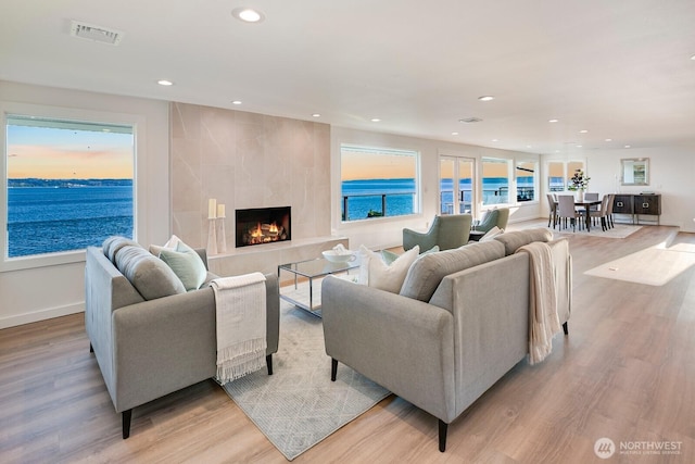living area with recessed lighting, visible vents, light wood-style flooring, and a fireplace