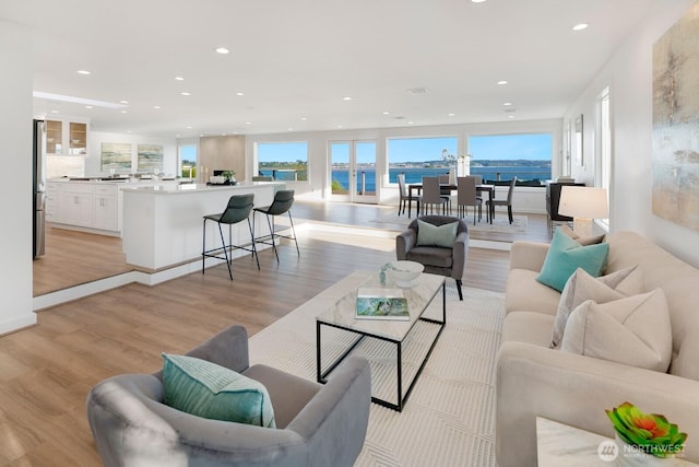 living room with recessed lighting, light wood-style floors, and a water view