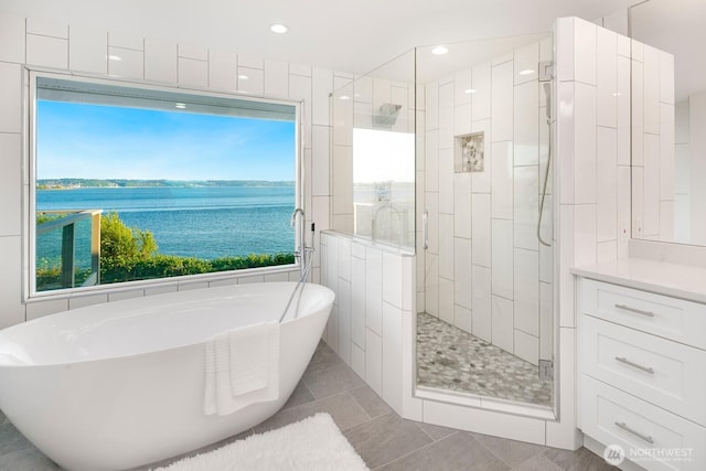 bathroom featuring a water view, tile patterned floors, a freestanding bath, and a shower stall