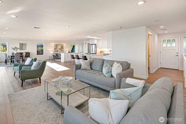 living room featuring recessed lighting, baseboards, visible vents, and light wood-style floors