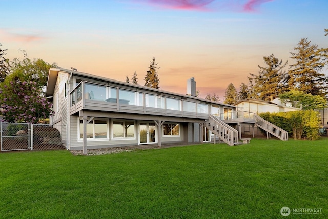 back of property with stairs, a lawn, and fence
