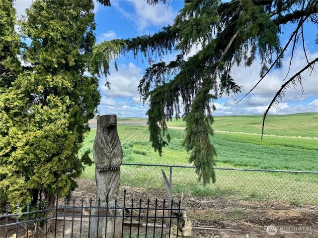 view of community with fence and a rural view