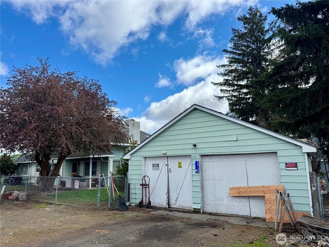 view of front of home featuring an outdoor structure, a garage, and fence