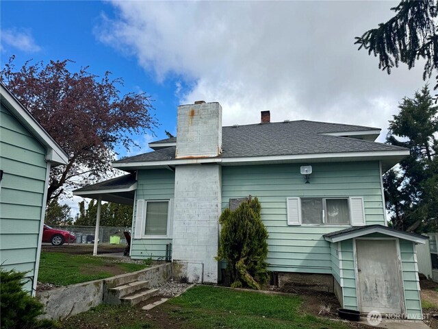 rear view of property with roof with shingles and a chimney