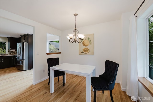 dining space with baseboards, an inviting chandelier, and light wood-style floors