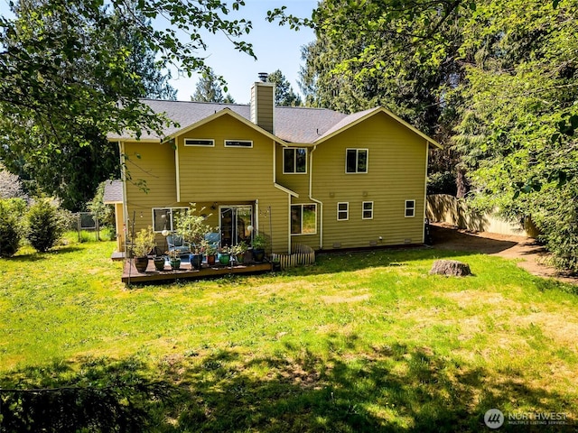 rear view of house with a lawn, fence, a chimney, and a deck
