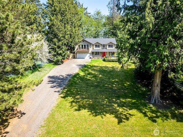 view of front of home with a porch, driveway, a front yard, and a garage