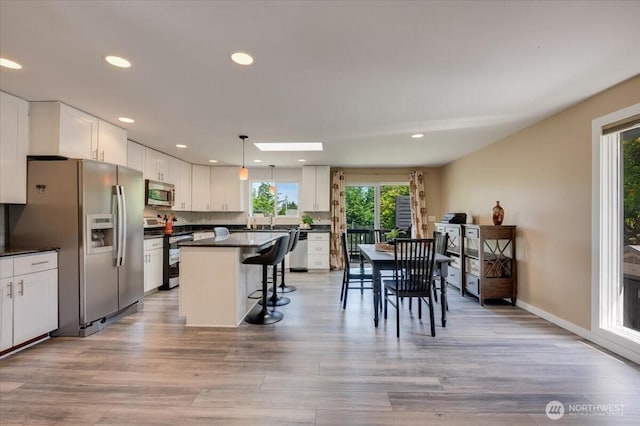 3507 222nd St SW, Mountlake Terrace, WA 98043 - kitchen with stainless steel appliances, plenty of natural light, dark countertops, a kitchen bar, and recessed lighting