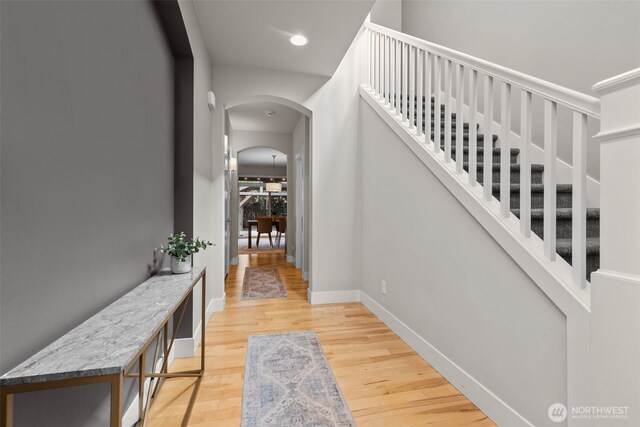 interior space featuring arched walkways, baseboards, stairs, and wood finished floors