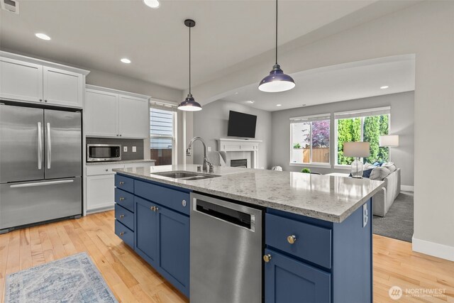 kitchen featuring a sink, stainless steel appliances, blue cabinetry, and open floor plan