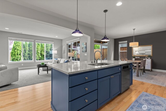 kitchen featuring open floor plan, a sink, dishwasher, and blue cabinetry