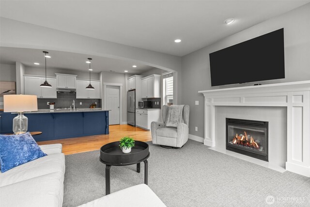 living area with recessed lighting, arched walkways, a fireplace with flush hearth, and light colored carpet
