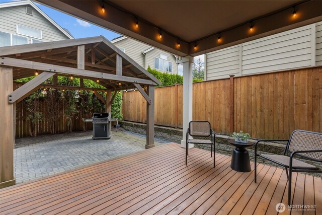 wooden deck with a gazebo, fence, and a patio area