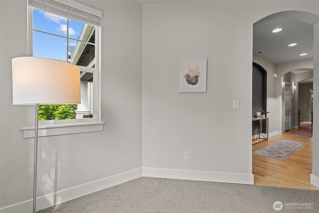 interior space featuring arched walkways, baseboards, and recessed lighting