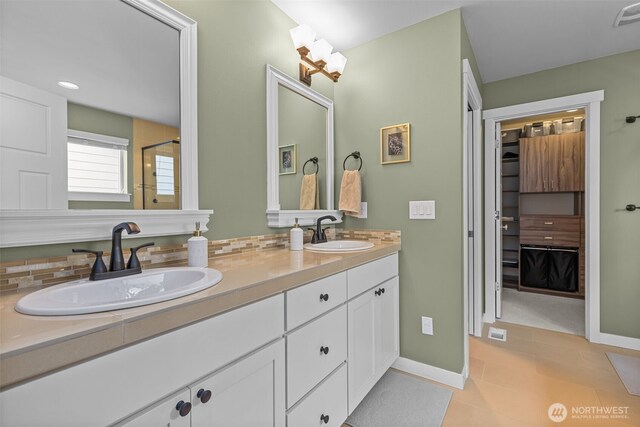 bathroom with baseboards, a sink, and a shower with shower door