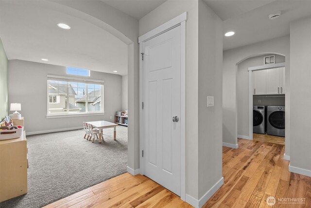 hallway with light wood-style floors, arched walkways, recessed lighting, baseboards, and washer and clothes dryer