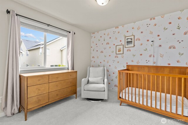 bedroom featuring wallpapered walls, light colored carpet, and a crib