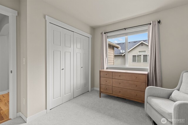 living area featuring baseboards and light colored carpet