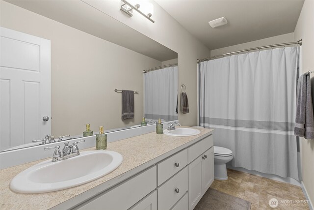 full bathroom with a sink, toilet, and double vanity