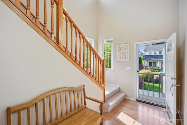 foyer featuring wood finished floors, baseboards, a high ceiling, and stairway